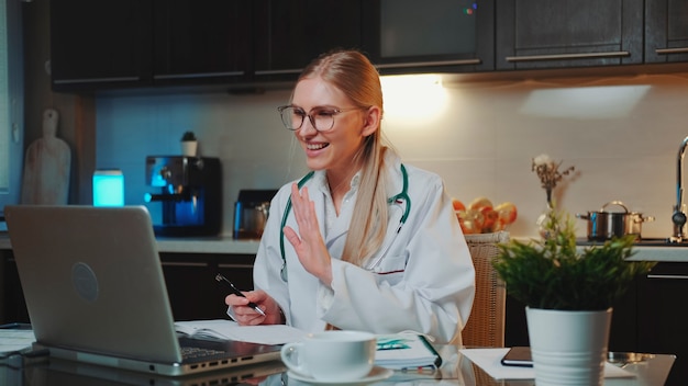 Female doctor in medical gown making video call to patient from\
home