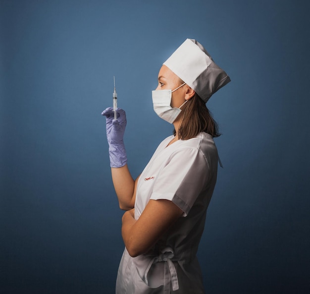 Female doctor in a medical mask holds a syringe in her hands. vaccination concept.