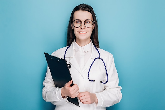 Female doctor or nurse in eyeglasses and white uniform holding clipboard