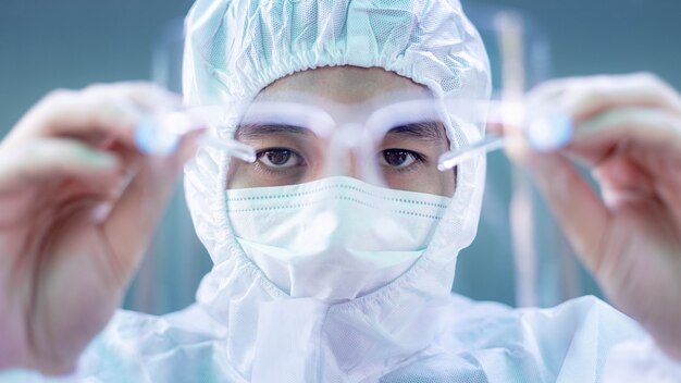 Female doctor or nurse wearing protective suit and protective mask and goggles banner to protect COVID-19 infection. Outbreak COVID-19, Medical, Healthcare and Quarantine concept.