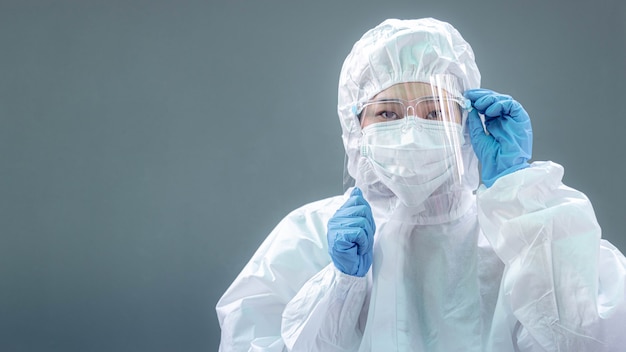 Female doctor or nurse wearing protective suit and protective mask and goggles banner to protect COVID-19 infection. Outbreak COVID-19, Medical, Healthcare and Quarantine concept.