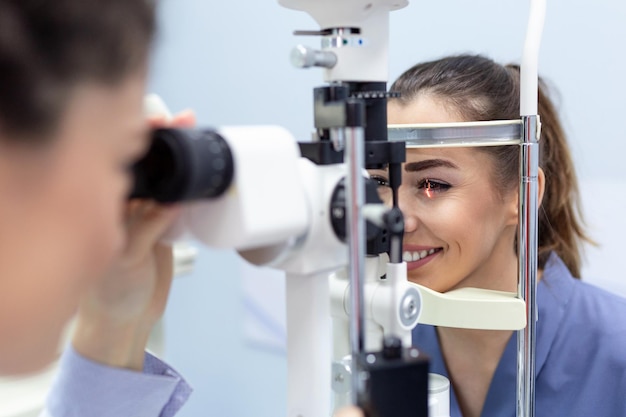 女性医師の眼科医は、現代のクリニックで魅力的な若い女性の目の視力をチェックしています眼科クリニックの医師と患者