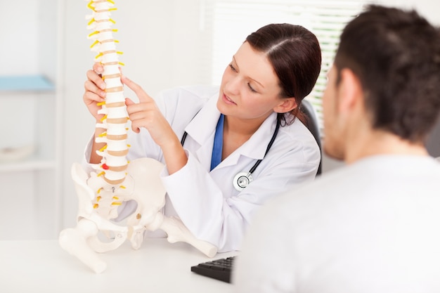 Female doctor pointing on bone in spine