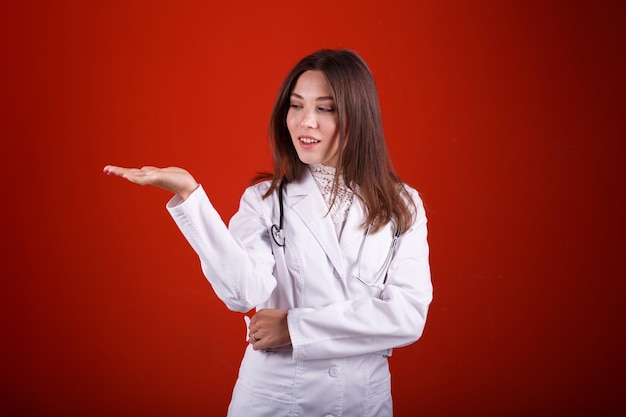 Female doctor pointing at something on a red background