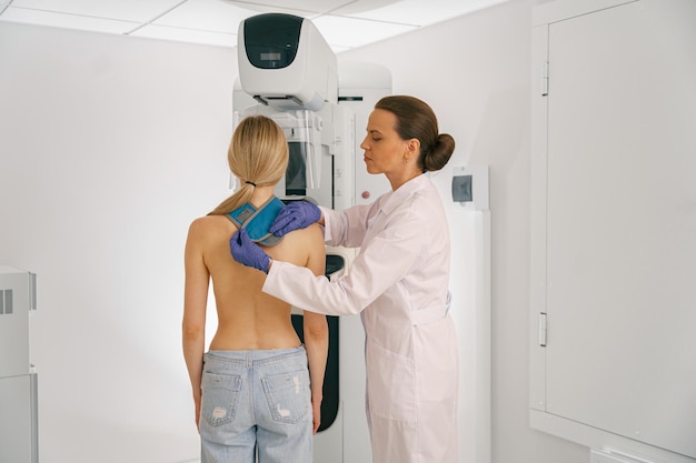 female doctor prepairing woman before doing mammogram xray to check for breast cancer at hospital