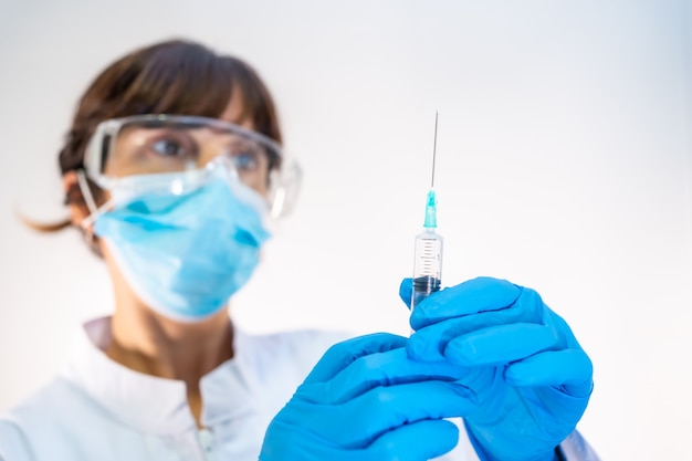 Female doctor preparing the injection of the coronavirus vaccine. Antibodies, immunize population.