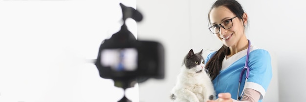 Female doctor present cute kitty on camera petting him for video