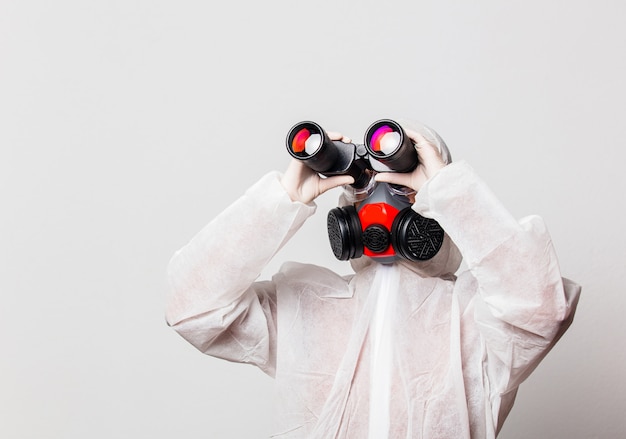 female doctor in protection suit and glasses with mask holds binoculars