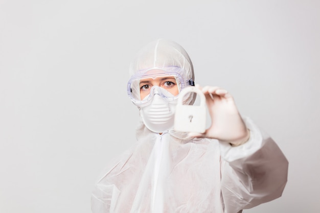 female doctor in protection suit and glasses with mask holds lock