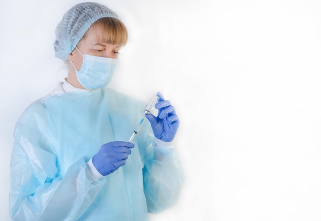 Female doctor in a protective blue suit with a syringe on a white background with copy space