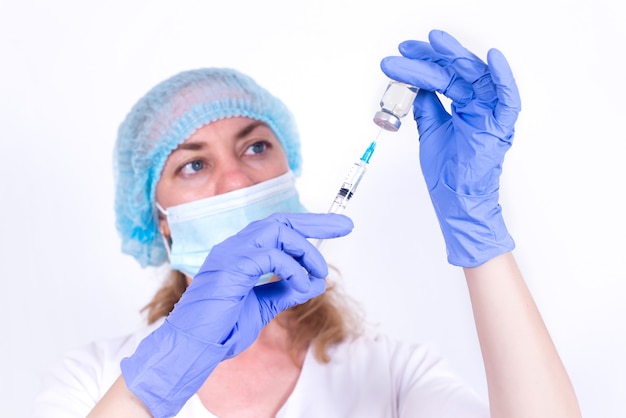 Photo female doctor in protective mask and gloves is typing vaccine into syringe closeup