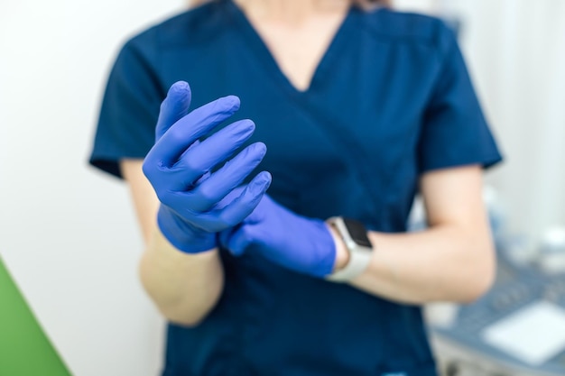 Female doctor puts on white gloves before a patient appointment
