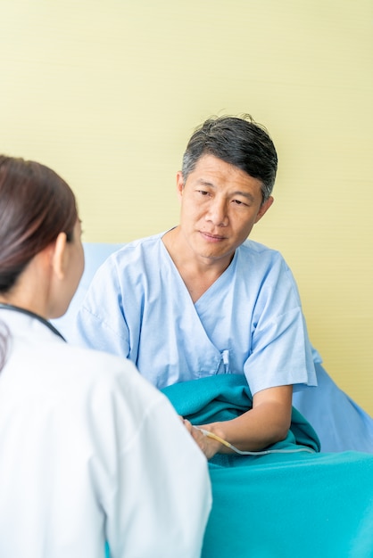 Medico femminile rassicurante sulla sua mano paziente senior