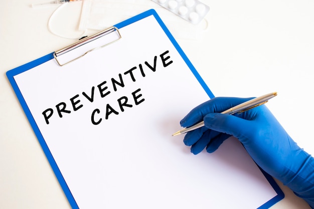 Female doctor's hand in a medical glove makes an inscription PREVENTIVE CARE in a document. Medical concept.