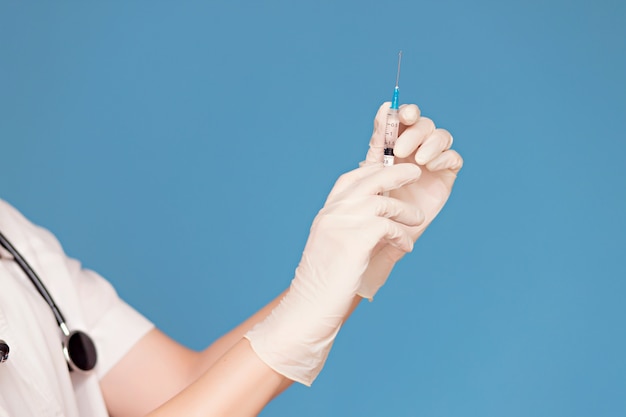 Female doctor's hands in white gloves hold an injection syringe. healthcare concept