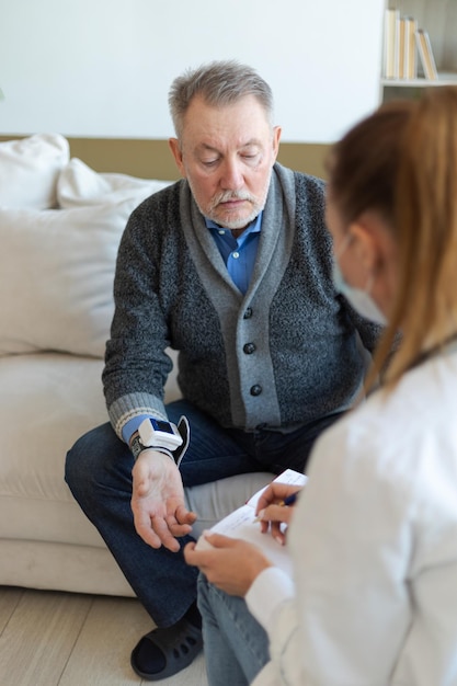 女医の年配の男性が診療所や自宅で血圧を測る老人患者とd