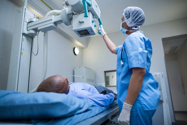 Female doctor sets up the machine to x-ray over patient