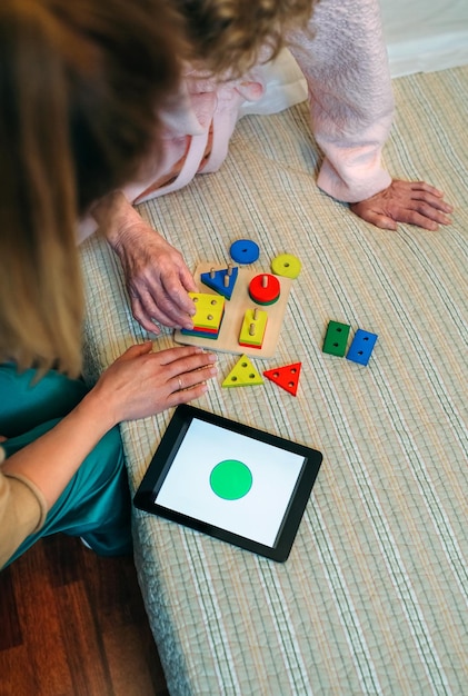 Female doctor showing geometric shape game to elderly female patient with dementia