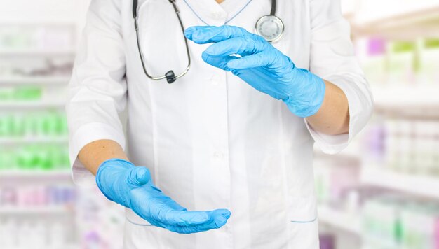 Female doctor showing something in her hand. Doctor empty palm in medical gloves. Medical professional handed holding virtual object.