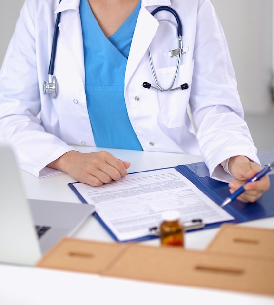 Female doctor sitting on the desk and working a laptop