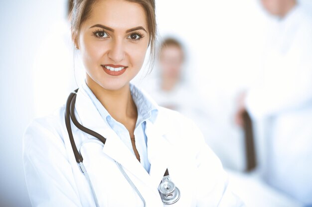 Female doctor smiling on the background with patient in the bed and two doctors.