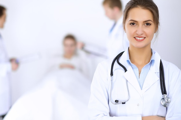 Female doctor smiling on the background with patient in the bed.