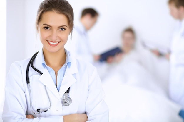 Female doctor smiling on the background with patient in the bed.