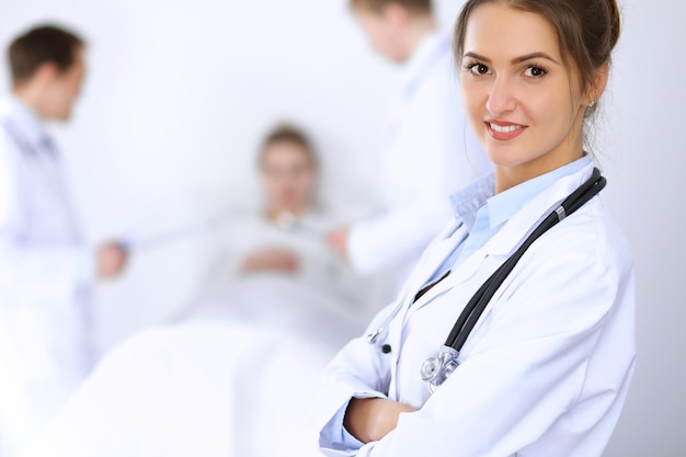 Female doctor smiling on the background with patient in the bed.