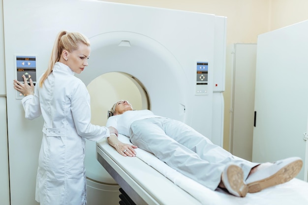 Female doctor starting CT scan procedure of senior patient at medical clinic