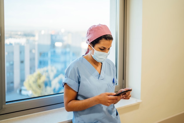 Female doctor surgeon using smart phone.