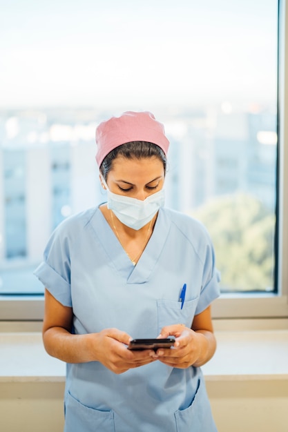 Female doctor surgeon using smart phone.