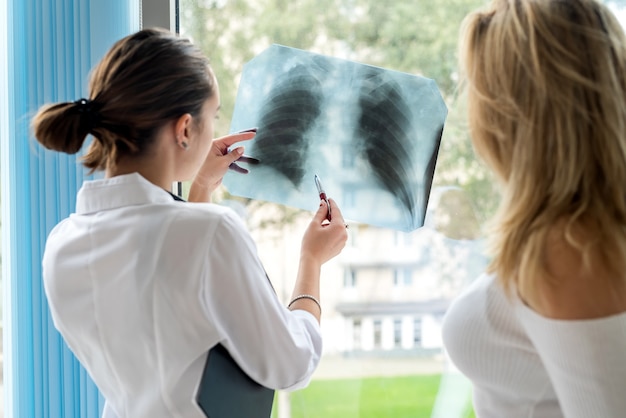 Female doctor talking patient about analyzing xray chest scan. Healthcare