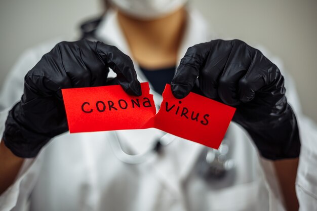 Female doctor tearing a Coronavirus red paper