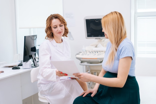 Female doctor transmits results of ultrasound examination to pregnant young woman