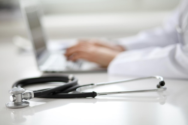 Female doctor typing on laptop, close up.