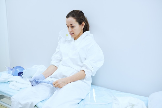 Female doctor in uniform sitting on bed in operating room