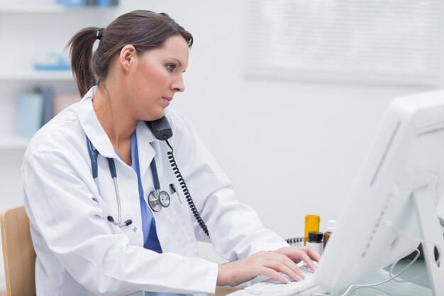 Female doctor using computer while on call at clinic