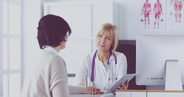 Female doctor using digital tablet talking with patients