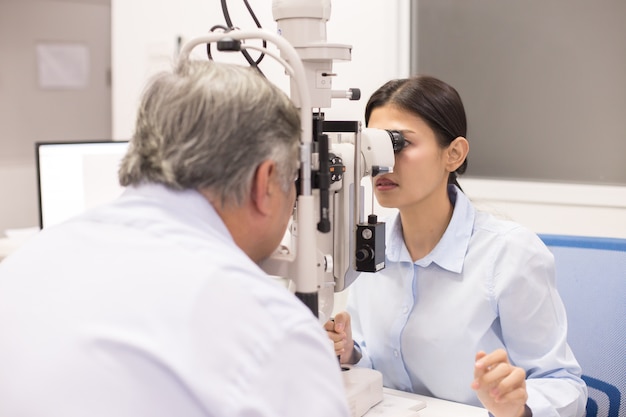 Female doctor using machine for check old man eye