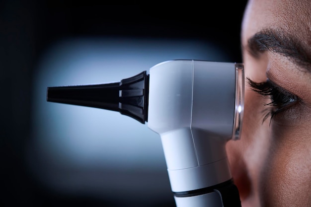 Female doctor using otoscope side view close up