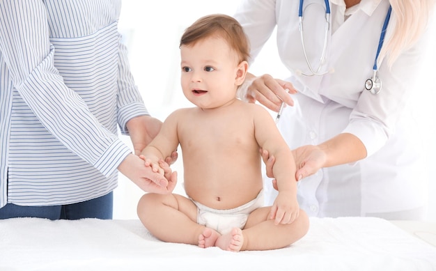female doctor vaccinating baby boy in clinic