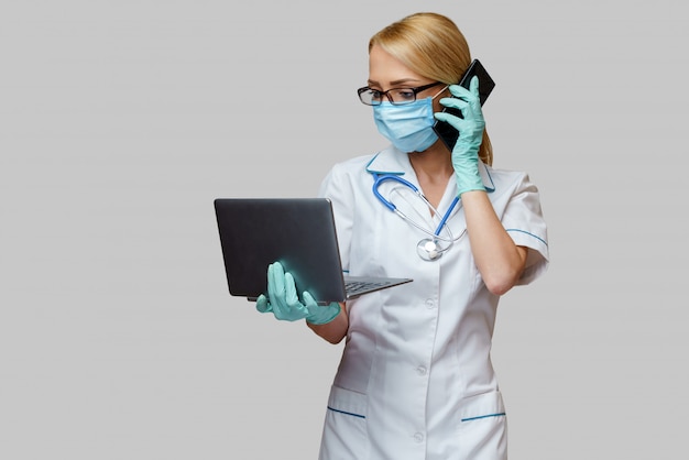 Фото Женский доктор носить защитную маску и перчатки и мобильный телефон