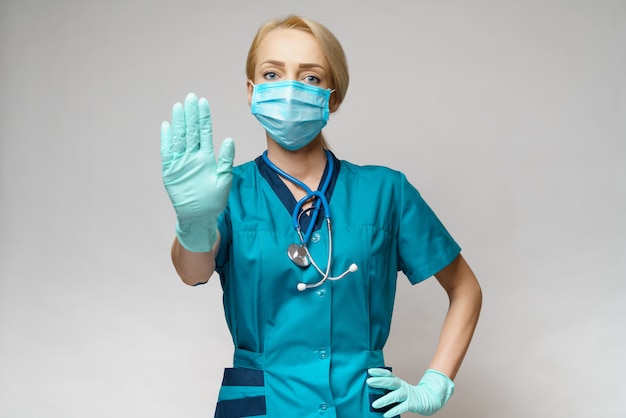 Female doctor wearing protective mask and latex gloves stop sign gesture