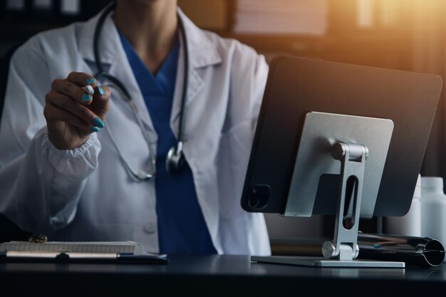 Female Doctor Wearing Scrubs In Hospital Corridor Using Digital Tablet