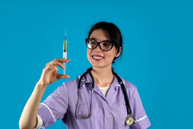 Photo female doctor wearing white coat holding syringe smiling isolated solid color background