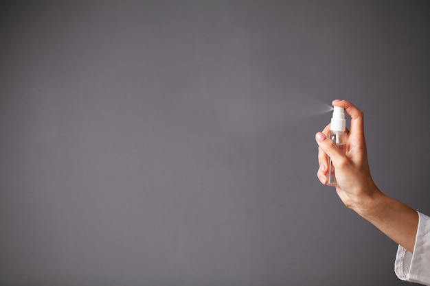 Female doctor in a white coat disinfects her hands with antiseptic