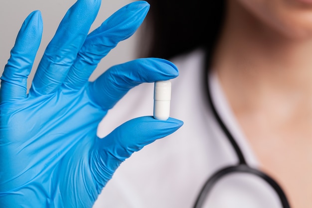 Female doctor in a white coat holding white pills for weight loss