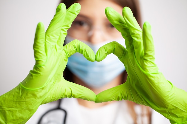 Female doctor in white coat shows hand a heart sign