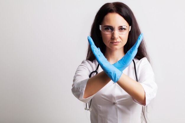 Medico femminile in camice mostra le mani fermare il gesto