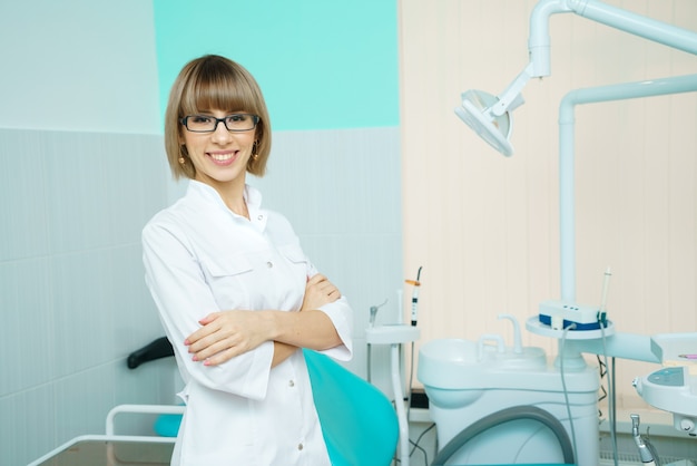 A female doctor in a white uniform is smiling against the background of an office. Health concept.